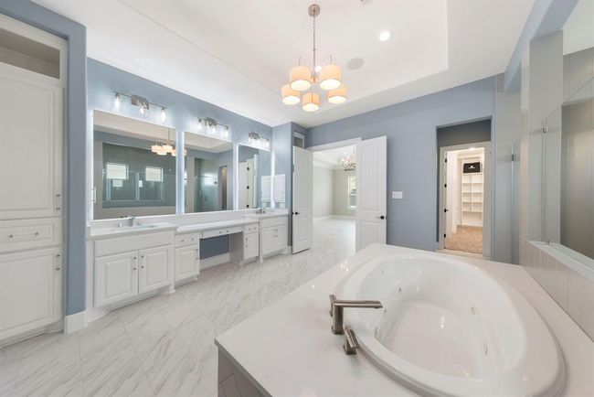 A true retreat, this spa-inspired primary bath offers a deep jetted soaking tub, two-way walk-in shower, oversized vanities, and a custom walk-in closet. | Image 23