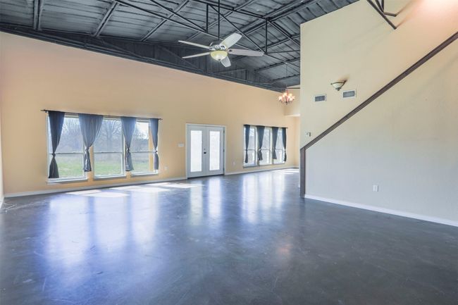 Unfurnished living room with finished concrete flooring, a high ceiling, visible vents, and baseboards | Image 4