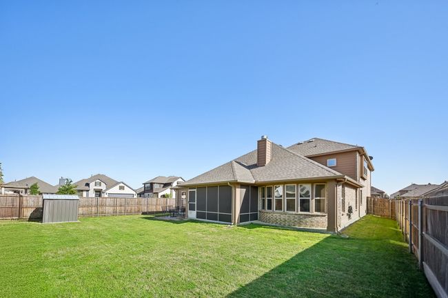 Back of property with a shingled roof, a sunroom, a lawn, a chimney, and a fenced backyard | Image 35