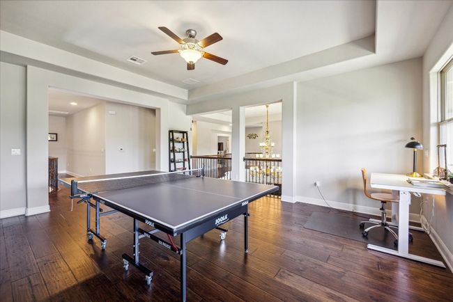 Rec room with ceiling fan with notable chandelier, visible vents, baseboards, and wood-type flooring | Image 22