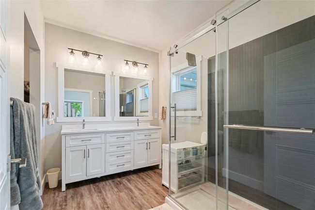 Bathroom featuring double vanity, a stall shower, and wood finished floors | Image 18