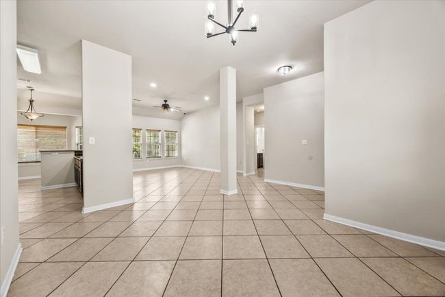 Unfurnished living room featuring light tile patterned floors, baseboards, recessed lighting, and ceiling fan with notable chandelier | Image 8