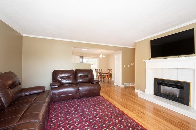 Living room featuring wood finished floors, ornamental molding, and a fireplace | Image 6