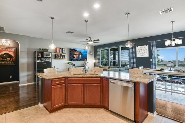 Kitchen with dishwasher, a sink, a chandelier, a ceiling fan, and open floor plan | Image 8