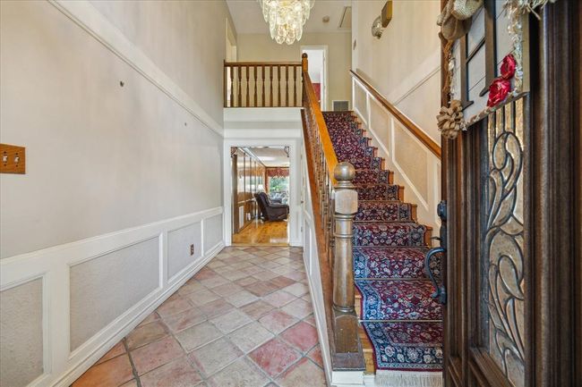Welcoming foyer, bright and airy, with saltillo tiled flooring and wood paneling leading to a cozy living area. Perfect for those who appreciate classic design elements. | Image 4