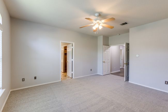 Master bedroom Unfurnished bedroom featuring light carpet, ensuite bathroom, and a ceiling fan | Image 28