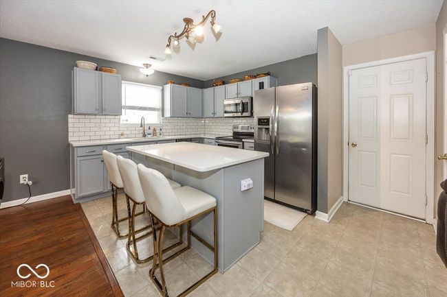 kitchen with a center island, a sink, tasteful backsplash, gray cabinetry, and appliances with stainless steel finishes | Image 8