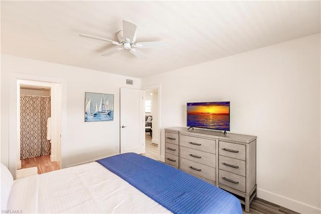 Bedroom with visible vents, light wood finished floors, baseboards, and ceiling fan | Image 14