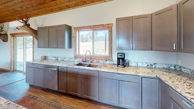 Kitchen with light stone counters, a sink, wooden ceiling, dishwasher, and dark wood finished floors | Image 9