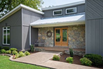 A covered porch and wooden double doors welcome you home! | Image 3