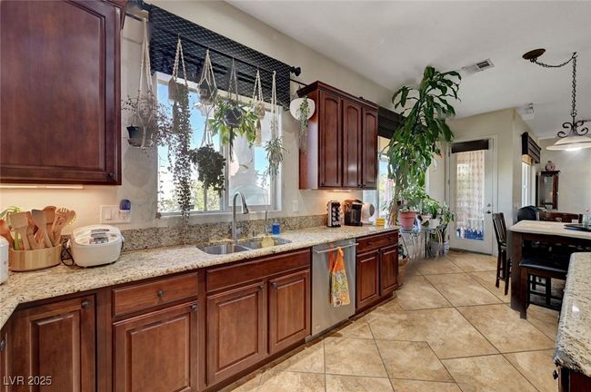 Kitchen featuring dishwasher, light tile patterned floors, light stone counters, and hanging light fixtures | Image 18