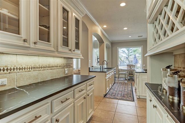 This Butler's Pantry seamlessly connects the dining room and kitchen, featuring custom cabinetry, undercabinet lighting, and ample counter space—perfect for entertaining. | Image 12
