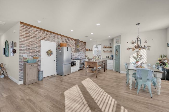 Kitchen featuring appliances with stainless steel finishes, wall chimney exhaust hood, light wood-style floors, and open shelves | Image 10