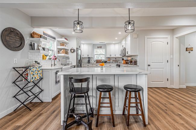 Kitchen featuring backsplash, wood finished floors, white cabinets, stainless steel appliances, and open shelves | Image 9