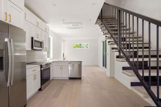 Kitchen with tasteful backsplash, baseboards, light wood-style flooring, stainless steel appliances, and a sink | Image 6
