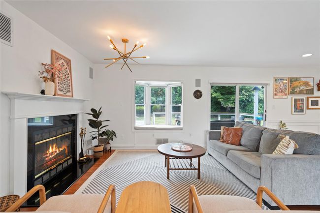 Living area featuring wood finished floors, a glass covered fireplace, and a chandelier | Image 8