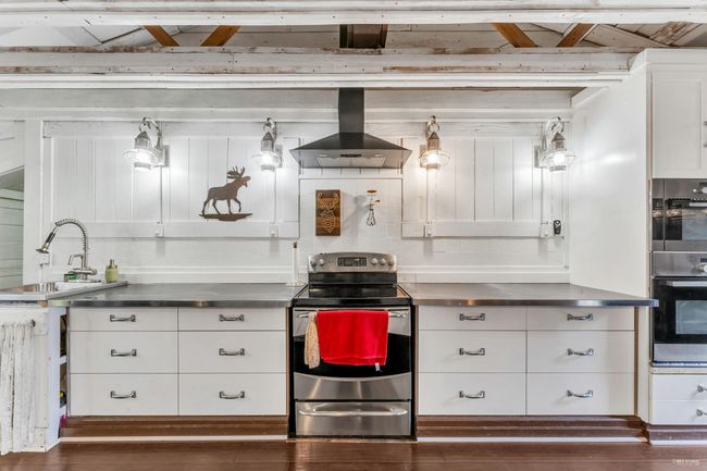 Kitchen featuring stainless steel counters, a sink, exhaust hood, and appliances with stainless steel finishes | Image 7