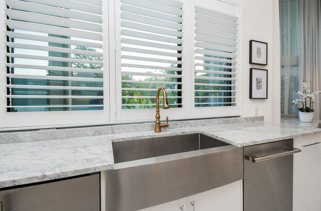 Stainless steel farm sink overlooks the backyard through plantation shutters. | Image 18