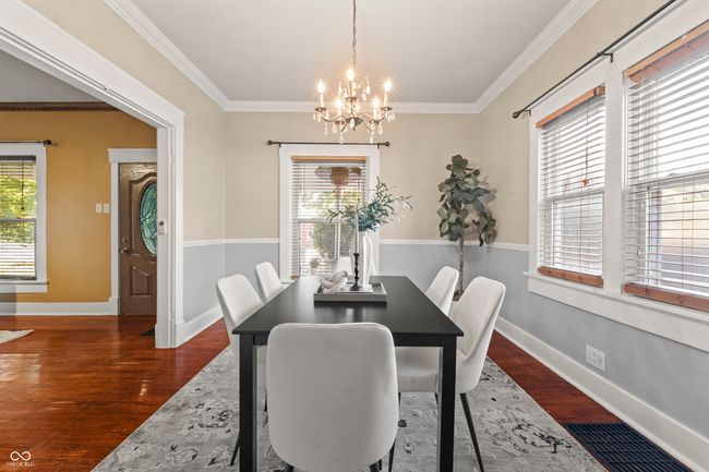 dining space featuring dark wood-type flooring, ornamental molding, and a chandelier | Image 13