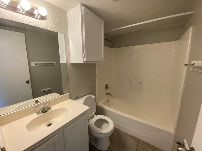 Bathroom featuring a textured wall, shower / bath combination, tile patterned floors, and vanity | Image 6