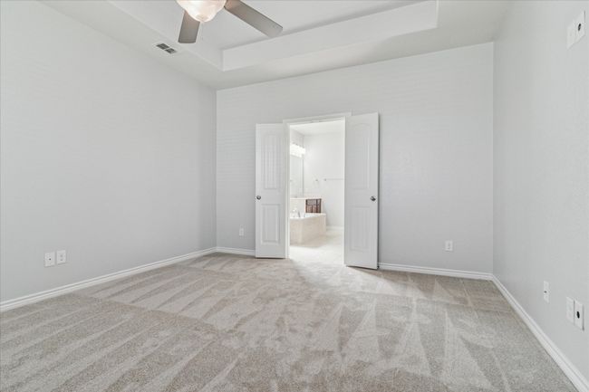 Primary bedroom featuring a raised ceiling, baseboards, and ceiling fan | Image 16