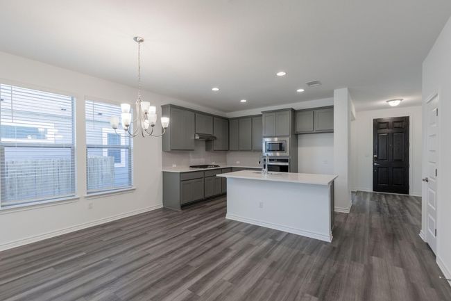 Kitchen with gray cabinets, under cabinet range hood, a chandelier, dark wood-style floors, and appliances with stainless steel finishes | Image 17