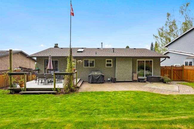 Rear view of house with a hot tub, a yard, fence, stucco siding, and a wooden deck | Image 26