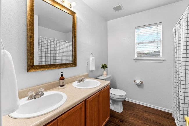 Full bath featuring double vanity, wood finished floors, and a shower with shower curtain | Image 26