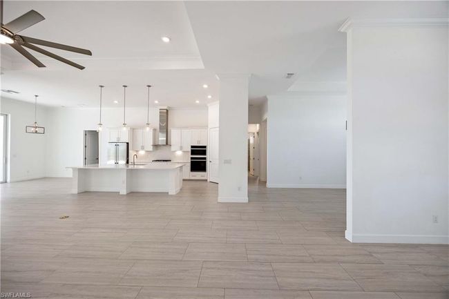 Unfurnished living room featuring crown molding, baseboards, ceiling fan, recessed lighting, and a sink | Image 8