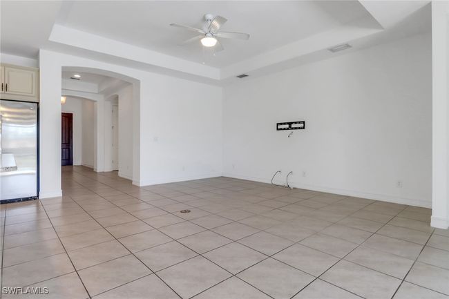 Unfurnished room with a raised ceiling, a ceiling fan, arched walkways, light tile patterned flooring, and baseboards | Image 19