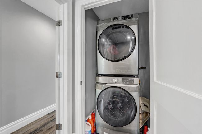 Washroom with stacked washer and clothes dryer, wood finished floors, and baseboards | Image 24