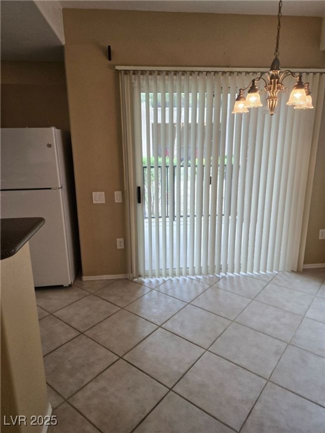 Unfurnished dining area featuring a chandelier, baseboards, and light tile patterned flooring | Image 13