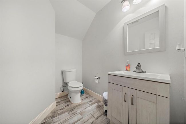 The downstairs half bath provides a convenient main-level option for guests, featuring a neutral color palette, single-sink vanity, and easy-to-maintain flooring that ties into the home’s cohesive design. | Image 29