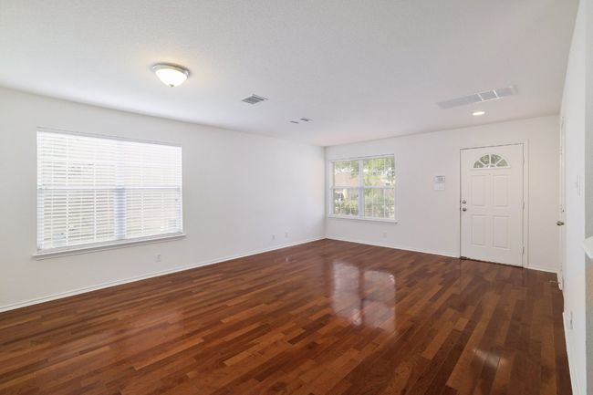 Empty room with visible vents, dark wood-style flooring, and baseboards | Image 5