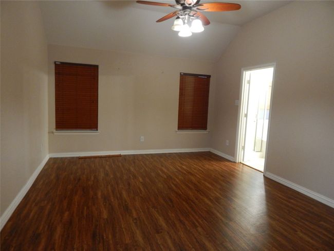 Empty room with ceiling fan, wood finished floors, and vaulted ceiling | Image 12