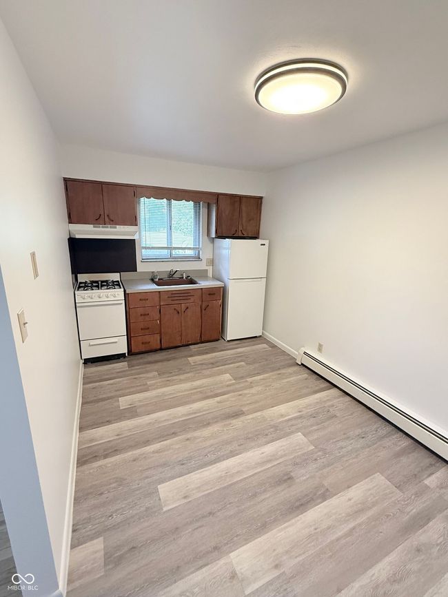 kitchen with a baseboard heating unit, white appliances, light wood-style flooring, and light countertops | Image 5