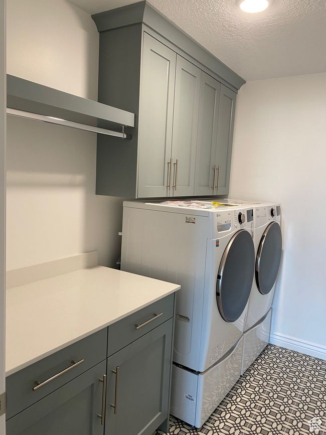 Clothes washing area featuring washing machine and dryer, baseboards, cabinet space, and a textured ceiling | Image 9