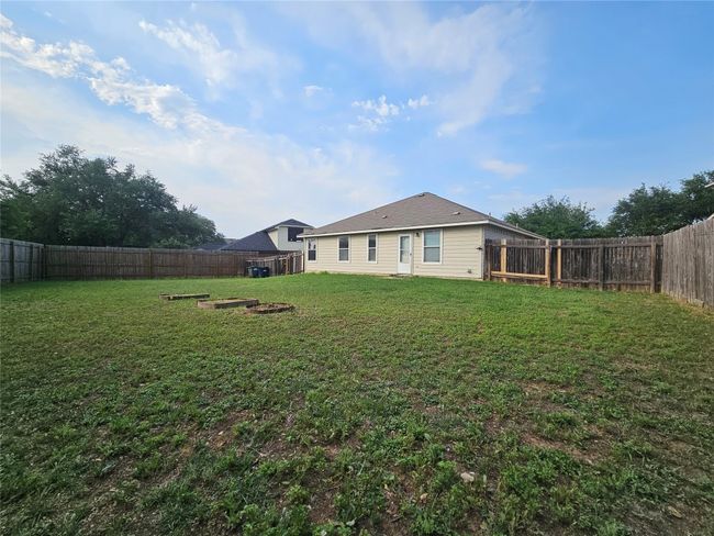 Fenced backyard with an outdoor fire pit | Image 5