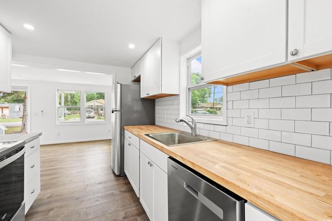Kitchen featuring stainless steel appliances, butcher block countertops, a sink, white cabinets, and recessed lighting | Image 8