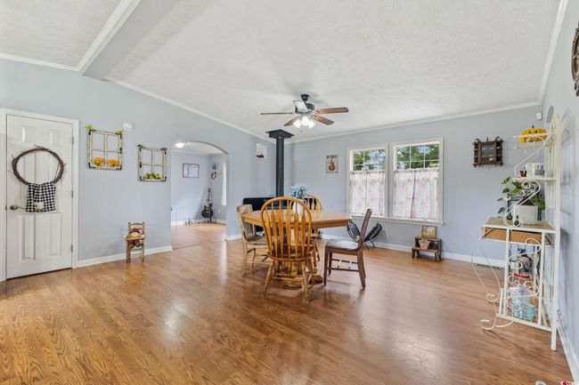 Living area with ceiling fan, ornamental molding, light wood finished floors, and a textured ceiling | Image 8