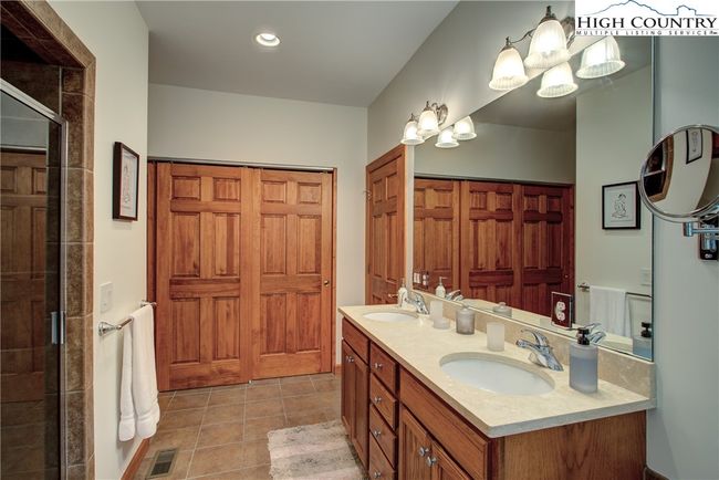 This spacious primary suite bathroom features double sinks, a large soaking tub and separate fully tiled shower. Closets are conveniently situated behind the sliding doors. | Image 33