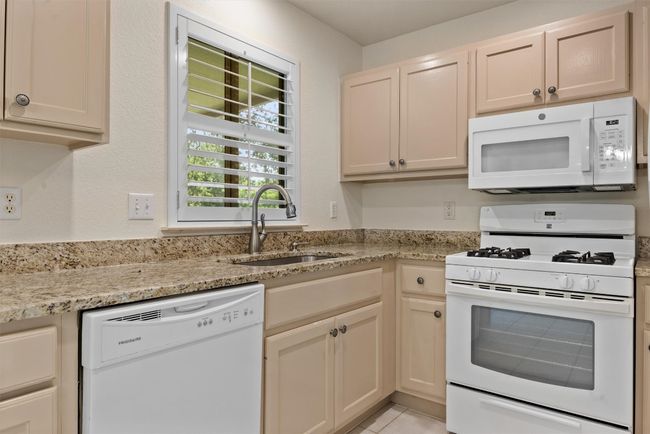 Kitchen featuring white appliances, light stone counters, and light tile patterned floors | Image 6