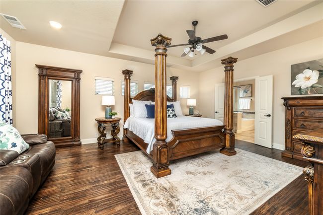 Bedroom with a raised ceiling, dark wood-style floors, baseboards, connected bathroom, and a ceiling fan | Image 15