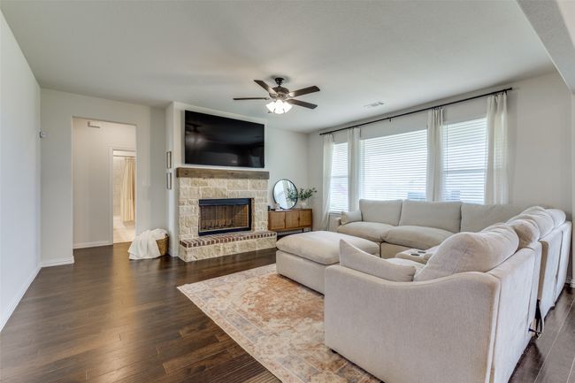 Living room with a ceiling fan, dark wood-style floors, and a fireplace | Image 10