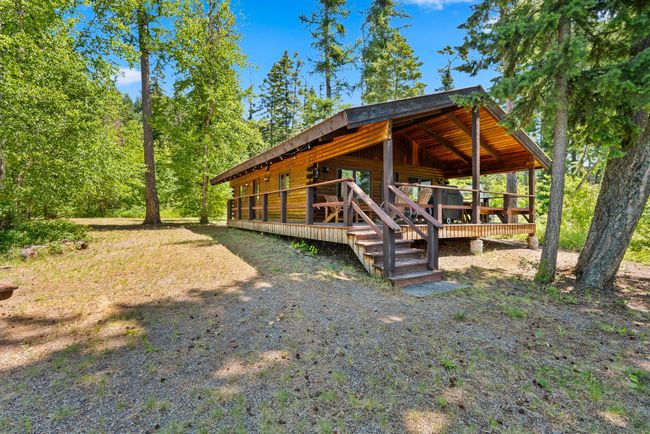 View of side of structure featuring a covered porch and forested area | Image 7