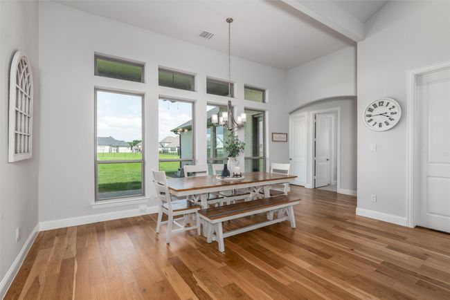 Dining space featuring a chandelier, light wood-type flooring, a high ceiling, and baseboards | Image 13