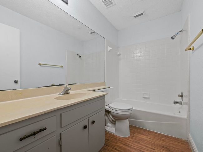 Full bath with wood finished floors, vanity, shower / tub combination, and a textured ceiling | Image 12
