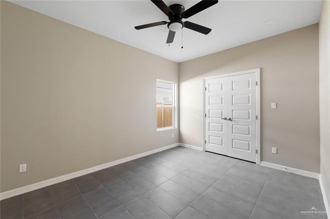 Unfurnished bedroom with dark tile patterned flooring, baseboards, and a ceiling fan | Image 9