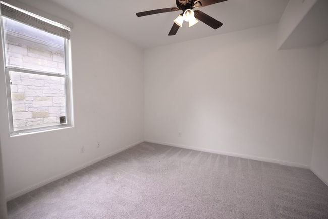 One of two secondary bedrooms both with ceiling fans, carpeting, and closet storage. | Image 14