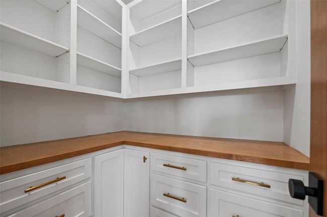 Spacious pantry with sleek white cabinetry, ample shelving, and elegant wood countertops—perfect for organized storage and easy access. | Image 16